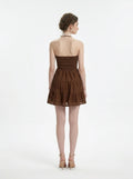 Back view of a woman in a brown halter neck tiered mini dress