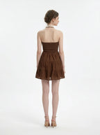 Back view of a woman in a brown halter neck tiered mini dress