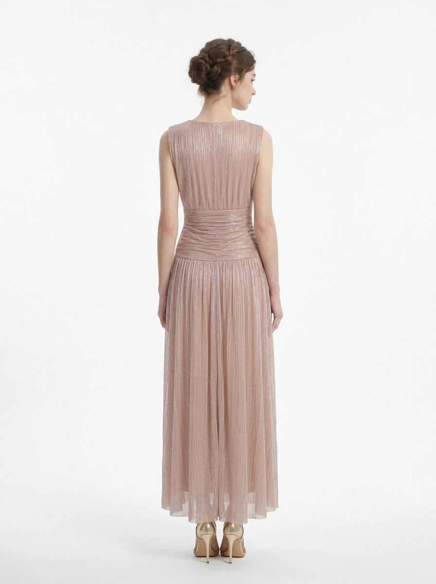 back view of a woman in a rose gold metallic a-line maxi dress with a v-neckline and ruched empire waist