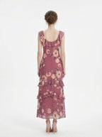 Back view of a woman in a floral print chiffon maxi dress with ruffled neckline and tiered skirt