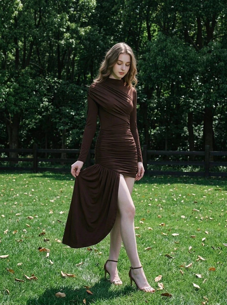 Model wearing a long-sleeved brown ruched mini dress with an asymmetrical hemline and high neckline, standing in a garden