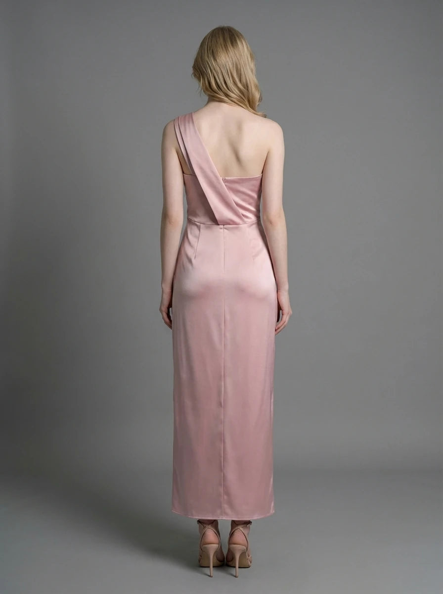 Woman wearing a dusty rose satin one-shoulder maxi dress with a high slit, standing against a grey background.