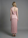 Back view of a woman in a dusty rose satin one-shoulder maxi dress with a high slit.