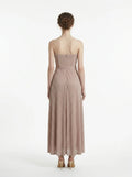 Back view of a woman in a strapless metallic knit A-line maxi dress with a self-tie belt