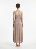 Back view of a woman in a strapless metallic knit A-line maxi dress with a self-tie belt
