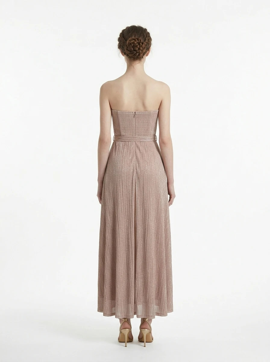 Back view of a woman in a strapless metallic knit A-line maxi dress with a self-tie belt