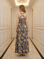 Back view of a woman in a grey floral print maxi dress with a lace-up back detail.