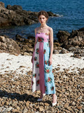 Woman standing on a rocky beach wearing a colorblock floral print maxi dress