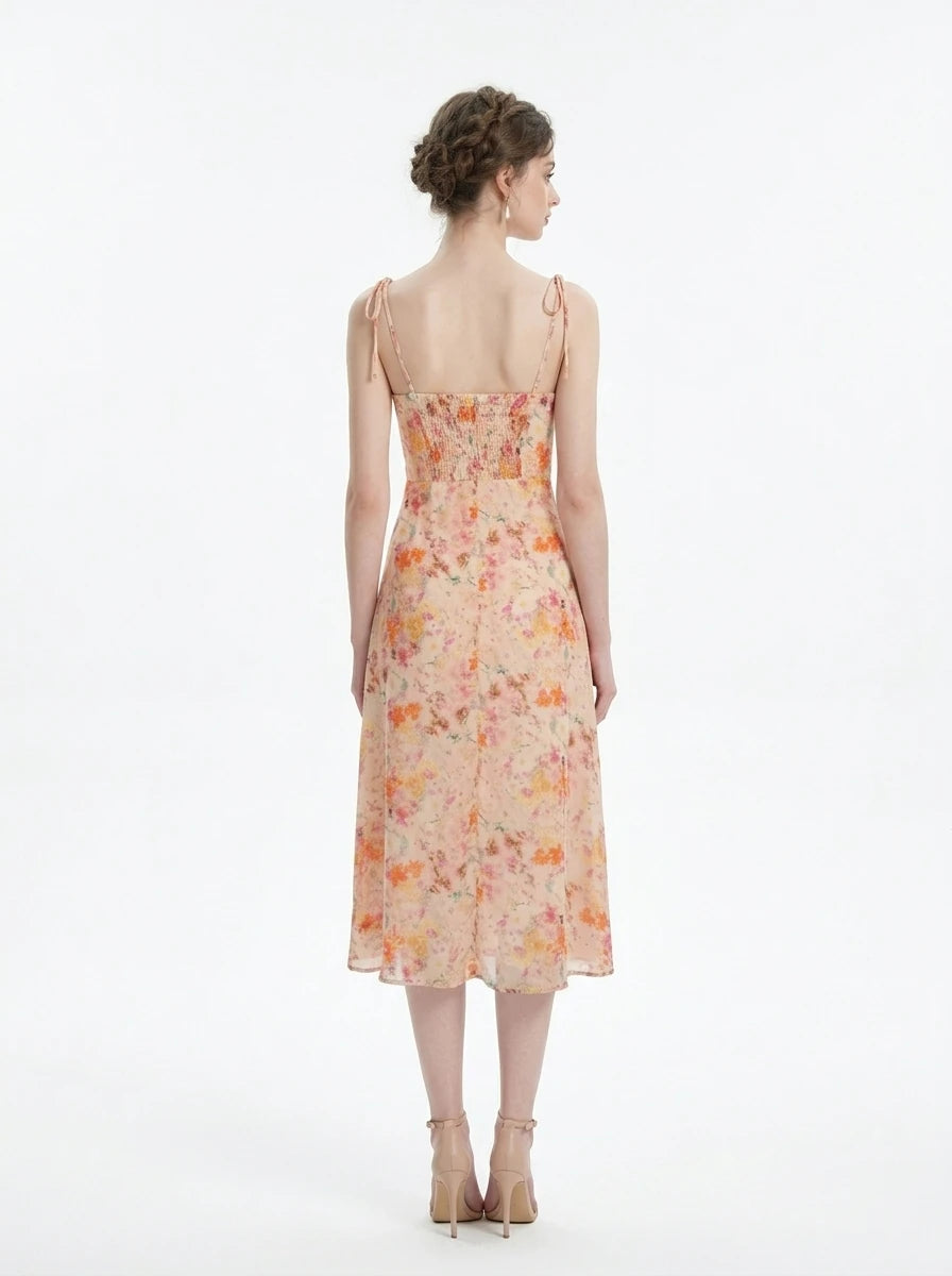 Woman wearing a peach floral print midi dress with sweetheart neckline and tie shoulder straps