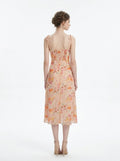 Back view of a woman in a peach floral print midi dress with smocked back