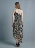 Back view of a woman in a floral print one-shoulder chiffon dress with a tiered, asymmetrical ruffle skirt.