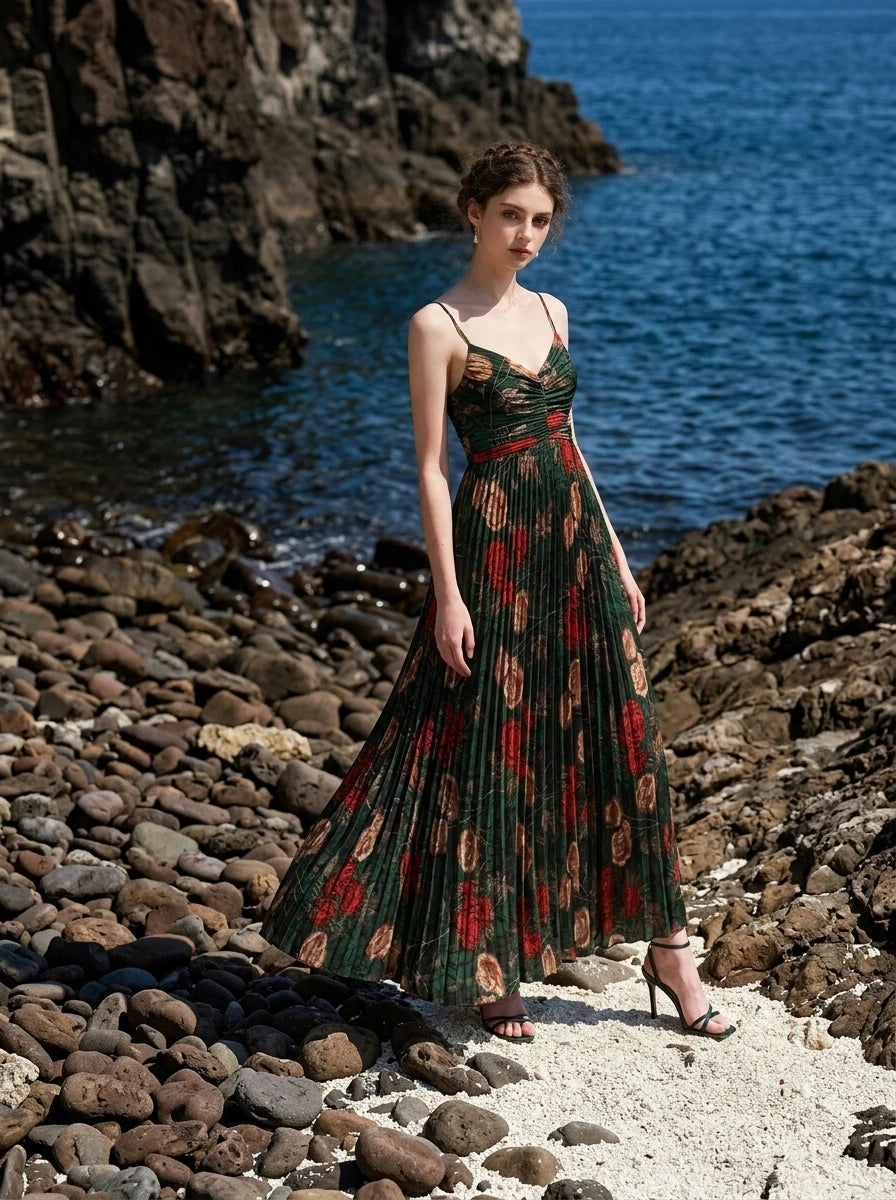 Woman in a dark green floral print maxi dress posing on a rocky beach