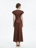 Back view of a brown polka dot midi dress with a v-neckline and ruffled sleeves.