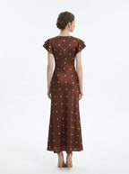 Back view of a brown polka dot midi dress with a v-neckline and ruffled sleeves.