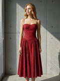 Woman posing by a window in a deep red linen blend midi dress, with light casting shadows