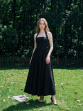 woman in a black midi halter dress standing in a garden