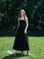 woman in a black midi halter dress standing in a garden