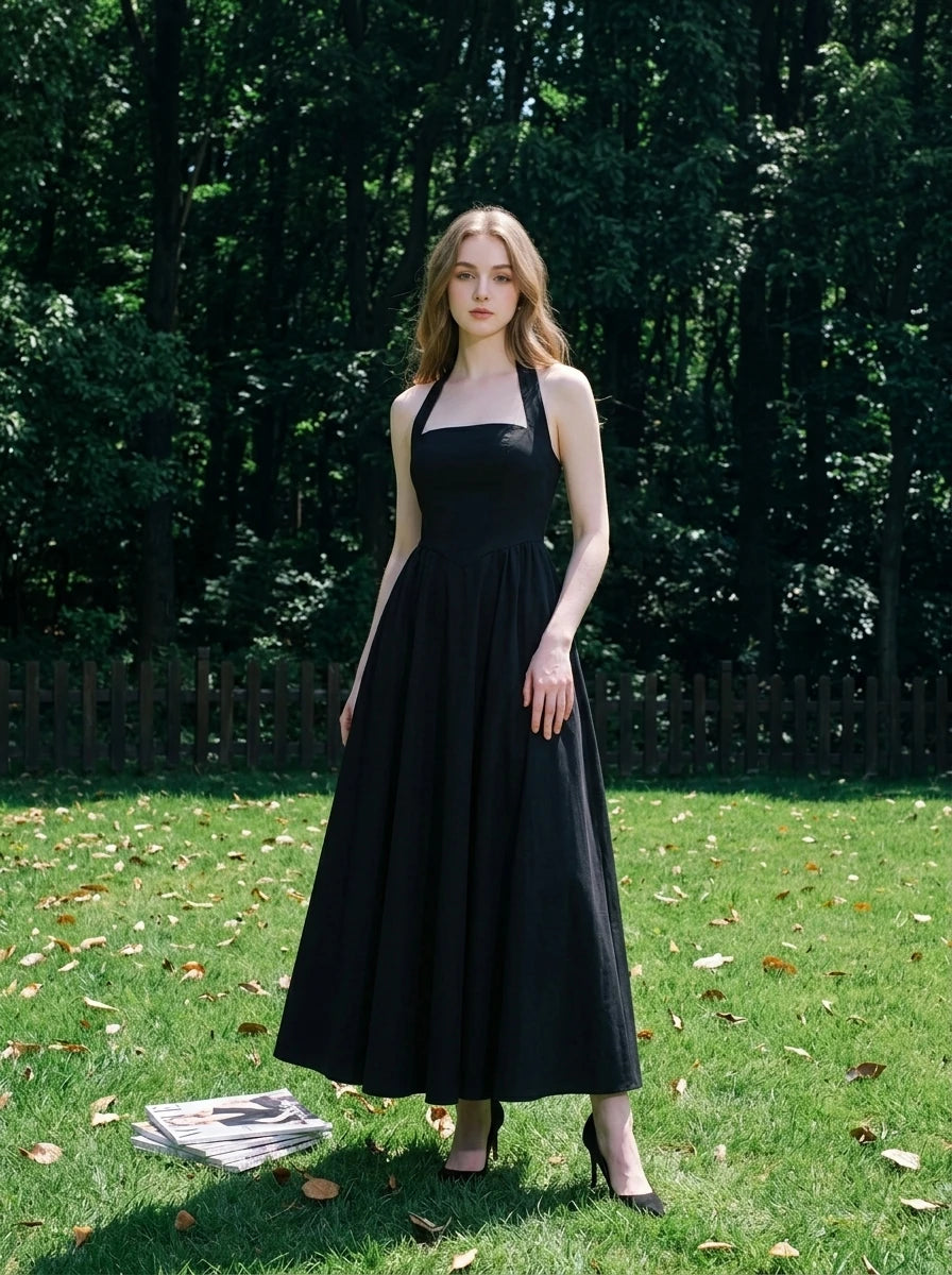 woman in a black midi halter dress standing in a garden