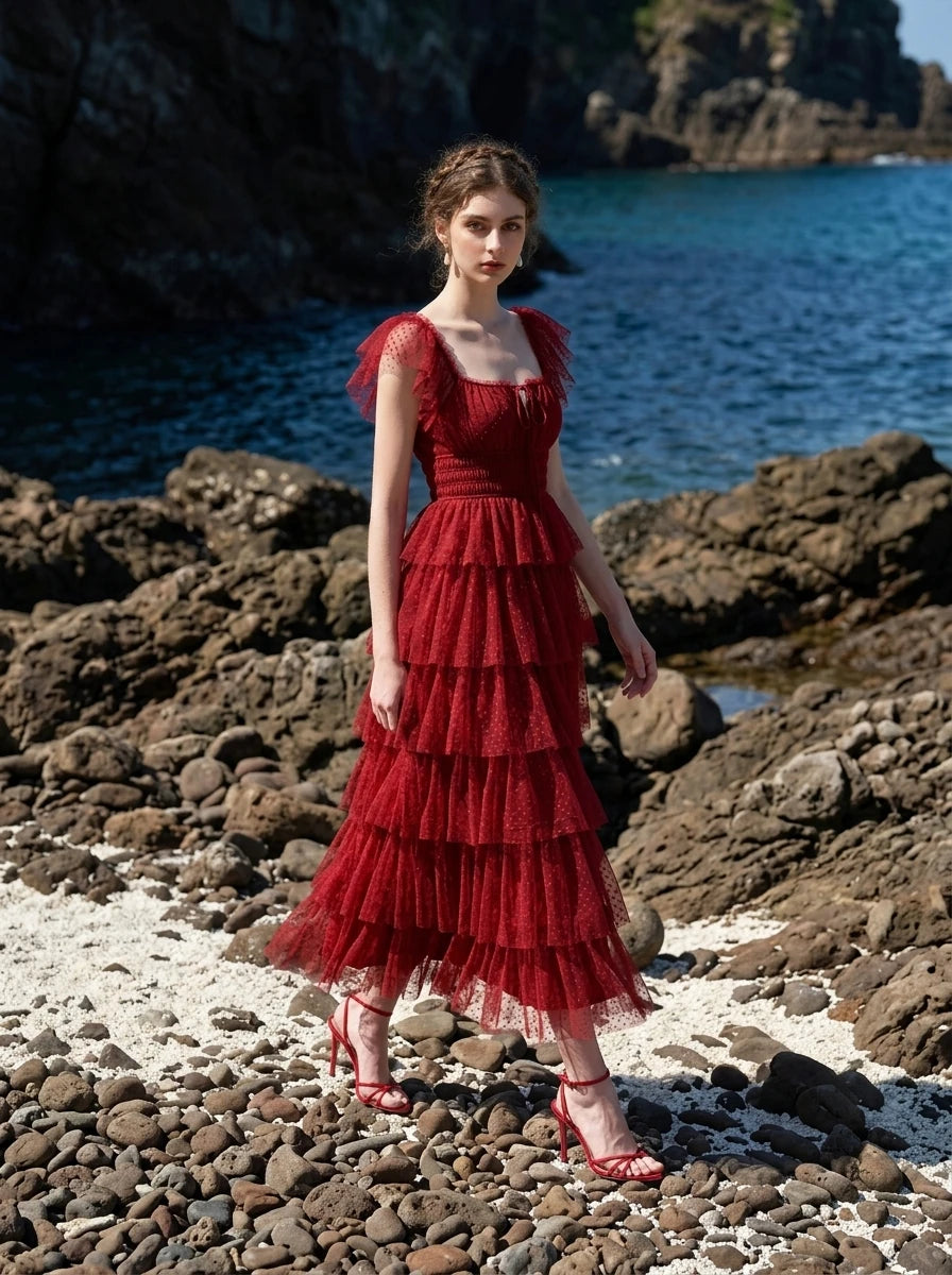 Woman walking on a rocky beach wearing a red tiered tulle dress