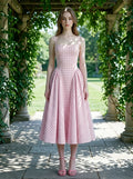 woman in a pink gingham dress standing in a garden archway