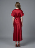 Woman in a red satin V-neck dress with kimono sleeves and a high slit, back view