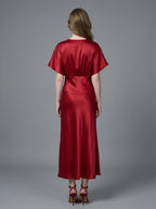 Woman in a red satin V-neck dress with kimono sleeves and a high slit, back view