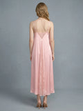 Back view of a woman in a pink satin slip dress with lace inserts.