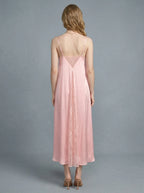 Back view of a woman in a pink satin slip dress with lace inserts.