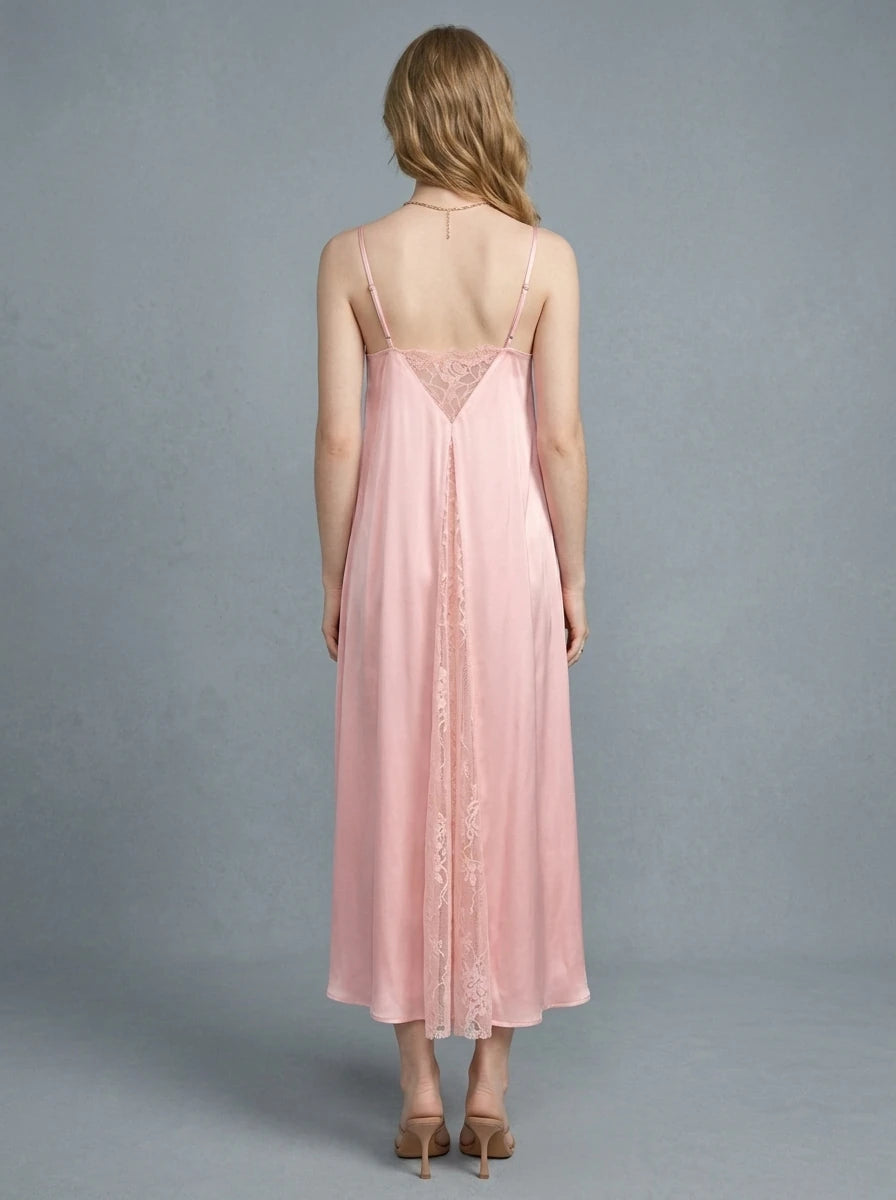 Back view of a woman in a pink satin slip dress with lace inserts.