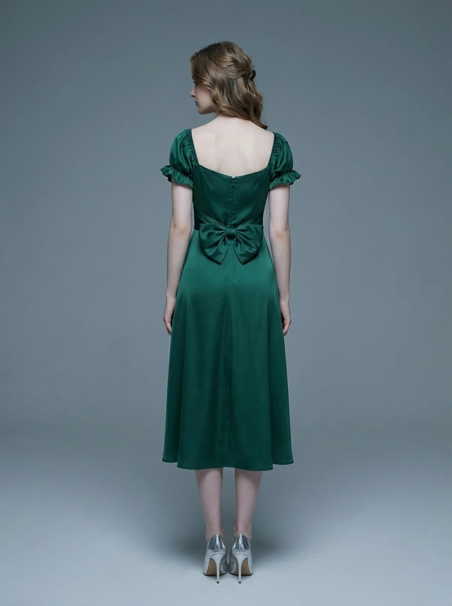 Rear view of a woman in a green satin midi dress with a large bow detail at the back and puff sleeves.
