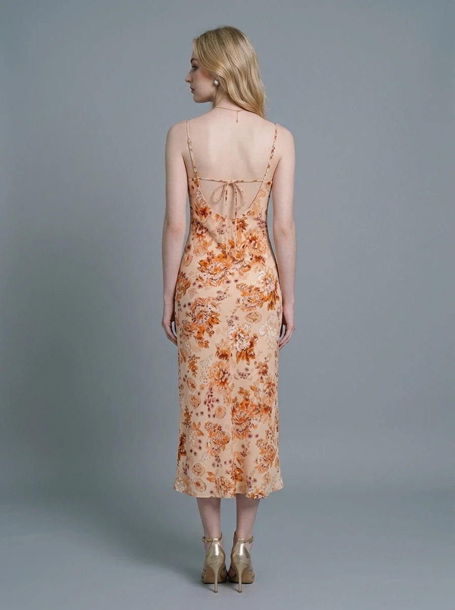Woman wearing a white slip dress with a blue floral print and a cowl neckline.