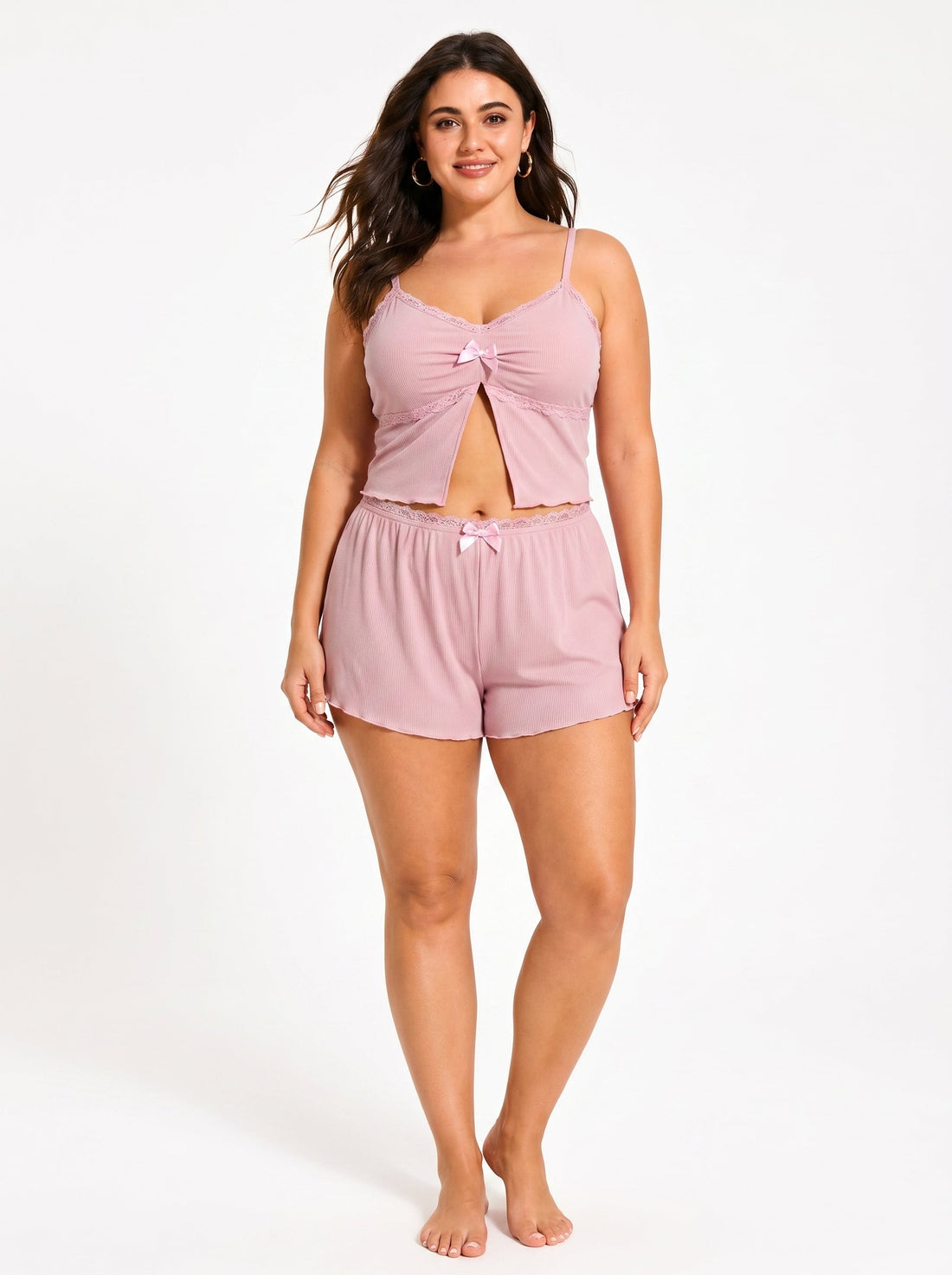 Plus-size woman wearing a pink ribbed knit cami top and shorts pajama set with lace trim and bow accents
