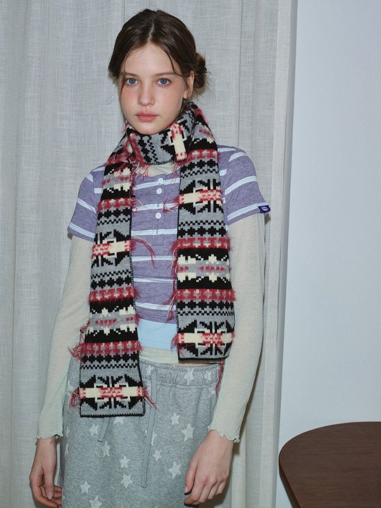 Woman poses with a long knit scarf adorned with ethnic-inspired motifs.