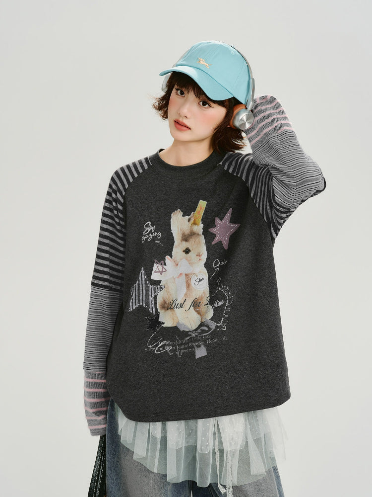 Woman wearing a dark grey long sleeve t-shirt with a graphic print of a bunny and stars.