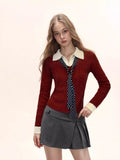 Woman wearing a red cable knit collared sweater with a white collar and cuffs, paired with a grey pleated skirt and a polka dot scarf.