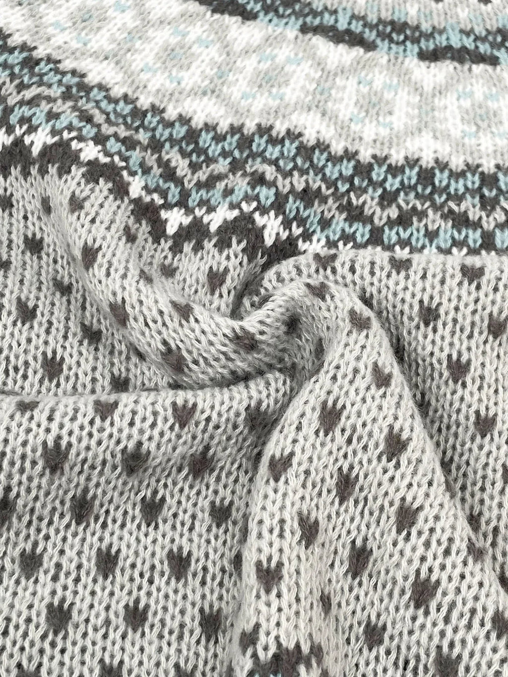 Close-up of the textured knit fabric of a grey sweater with a Fair Isle pattern