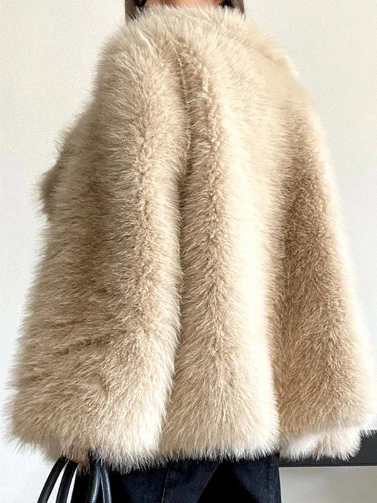 Close-up of a woman wearing a brown shaggy faux fur coat and holding a brown handbag.