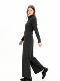 Woman wearing a charcoal grey knit loungewear set with a full zip jacket and wide leg pants, walking motion.