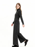 Woman wearing a charcoal grey knit loungewear set with a full zip jacket and wide leg pants, walking motion.