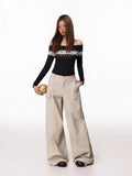 Woman posing with hands in pockets, wearing an off-the-shoulder sweater and wide-leg cargo pants.
