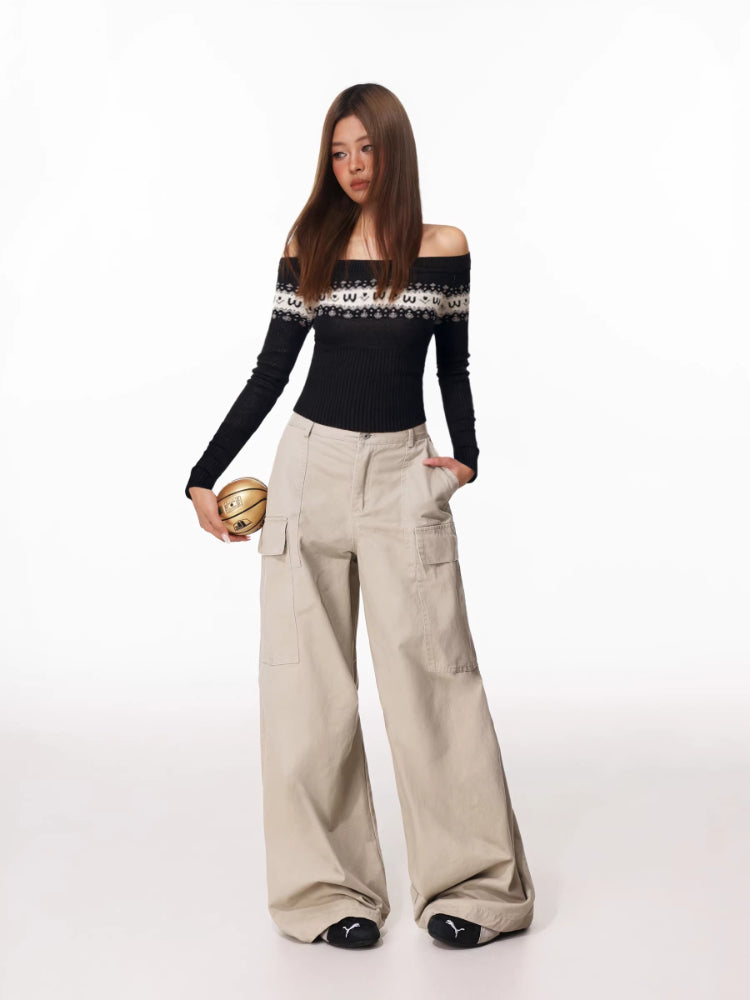 Woman posing with hands in pockets, wearing an off-the-shoulder sweater and wide-leg cargo pants.
