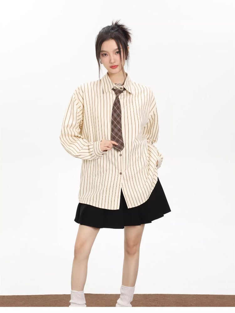 Woman wearing an oversized beige pinstripe button-down shirt with a brown plaid tie and a black skirt.