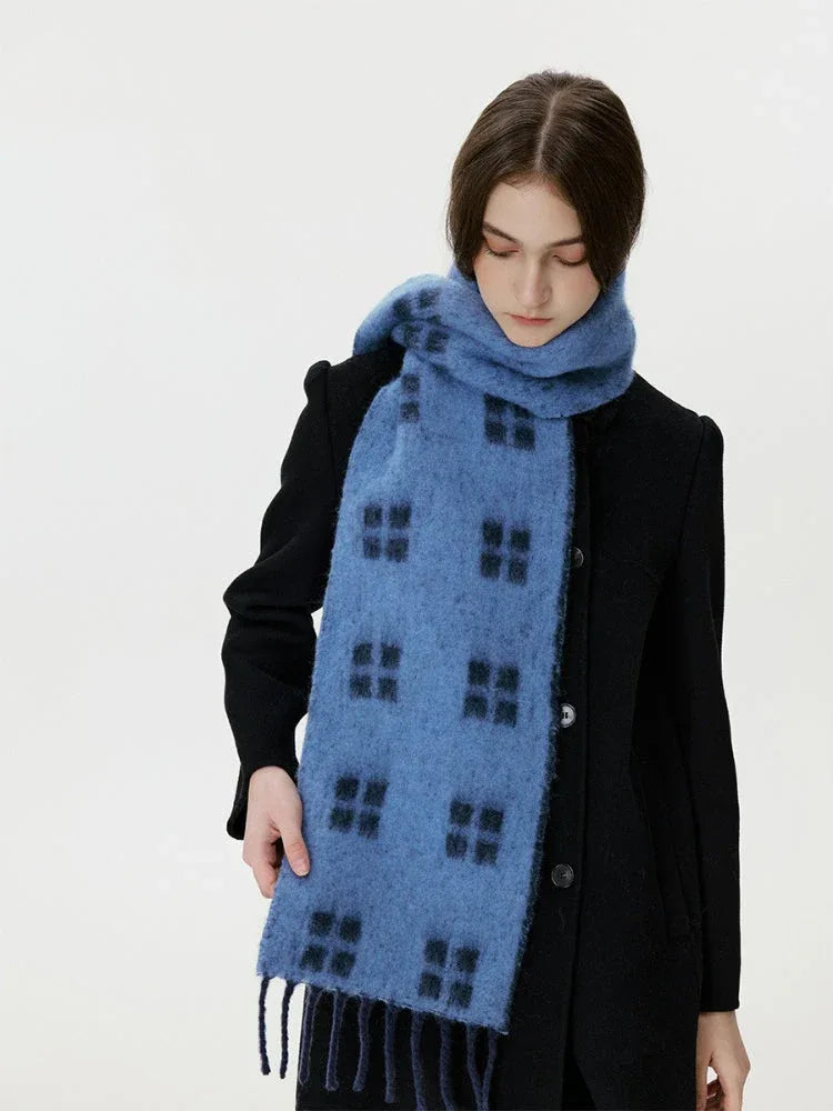 Woman adjusting a blue scarf with a black windowpane plaid pattern around her neck