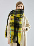 woman wearing a grey ribbed sweater and dark pants with a large plaid scarf draped around her neck
