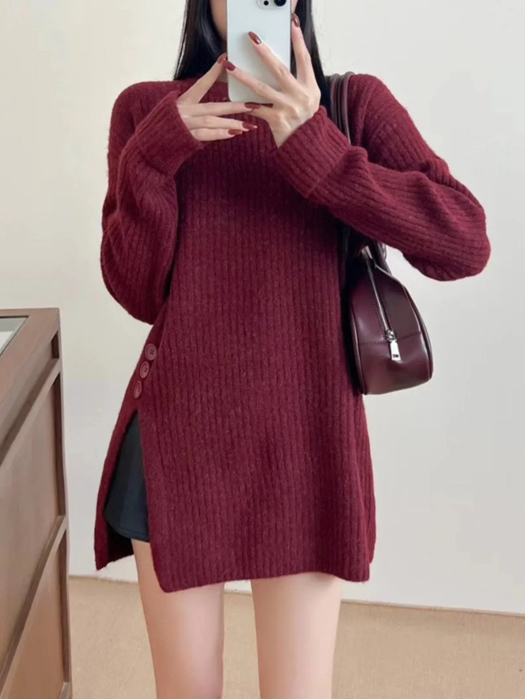 Model styled in a burgundy long-sleeve knit tunic with side slits.