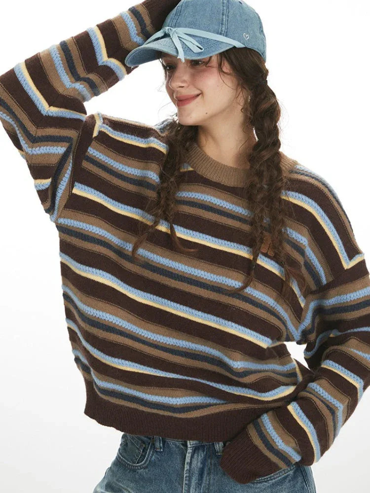 Woman adjusting her baseball cap while wearing a striped knit sweater.