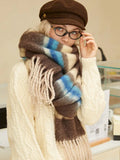 Close-up of a woman wearing a brown plaid scarf with beige, brown, and blue stripes.