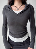Woman in a charcoal grey fitted hoodie with a zipper and ruched detailing, paired with a white base layer.