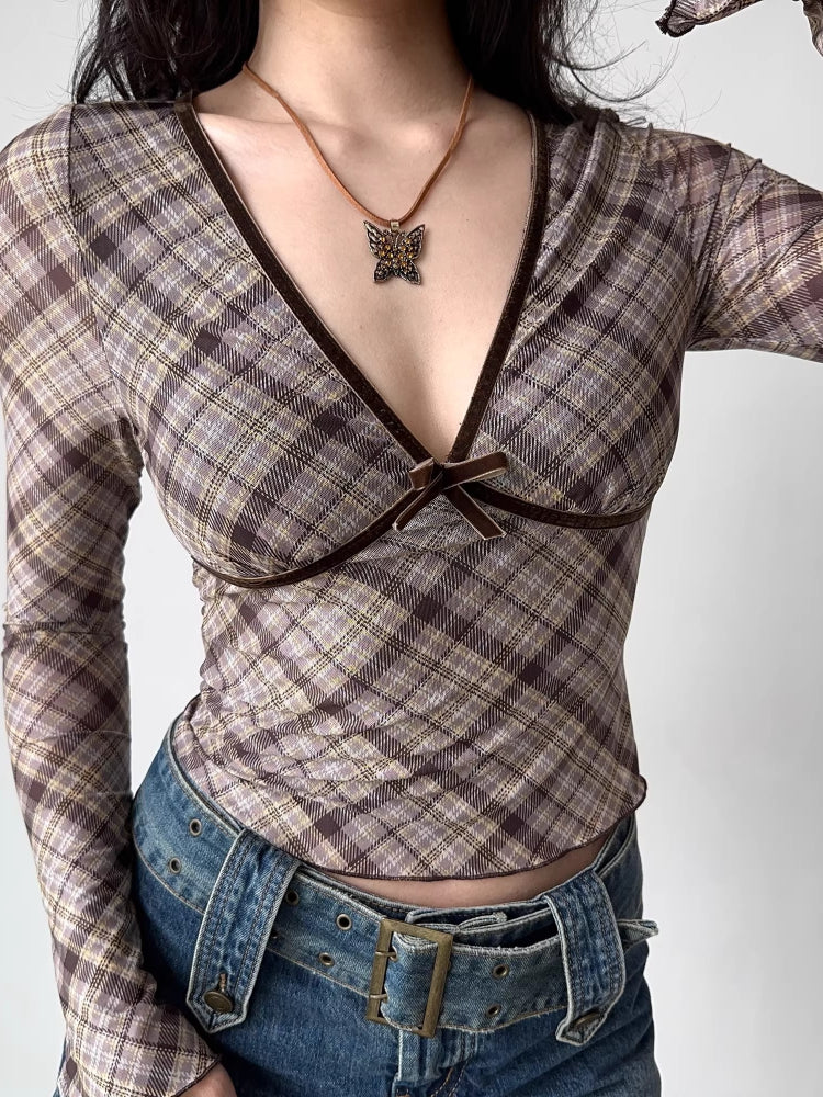 Model wearing a brown plaid long-sleeve top with a deep V-neck and velvet trim.