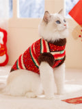 White Ragdoll cat wearing a red, green, and white striped knit sweater with brown fuzzy trim.